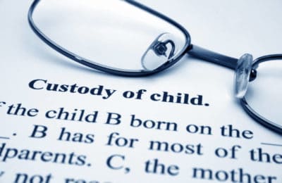 Document titled Custody of Child with a pair of thin square glasses laying face down above the title