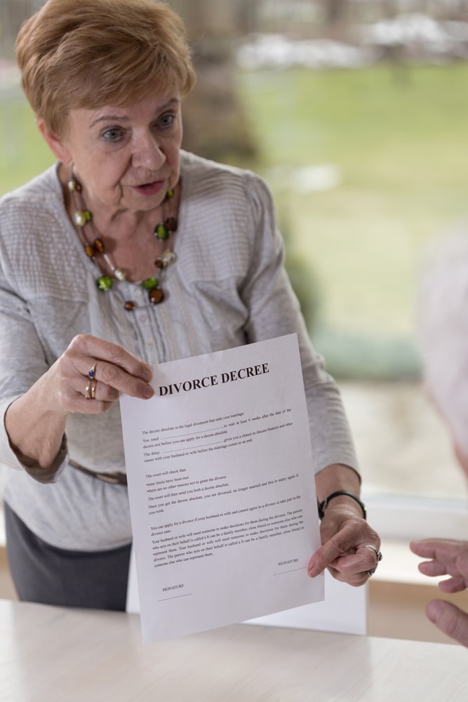 Elderly white woman holding up a divorce decree while talking